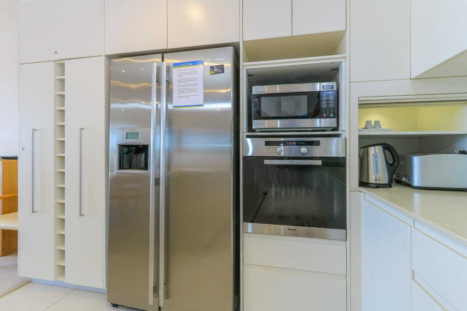 Kitchen with double door fridge, wall oven and microwave.