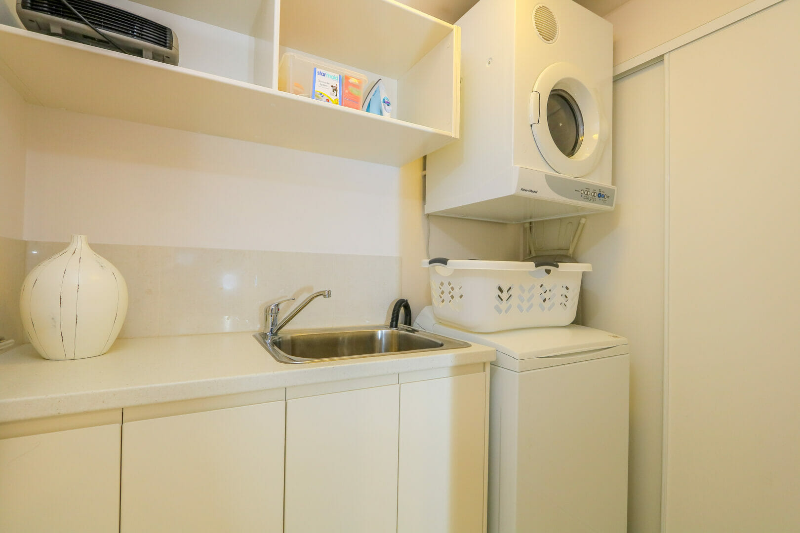 Laundry with washing machine, clothes dryer, bench and basin