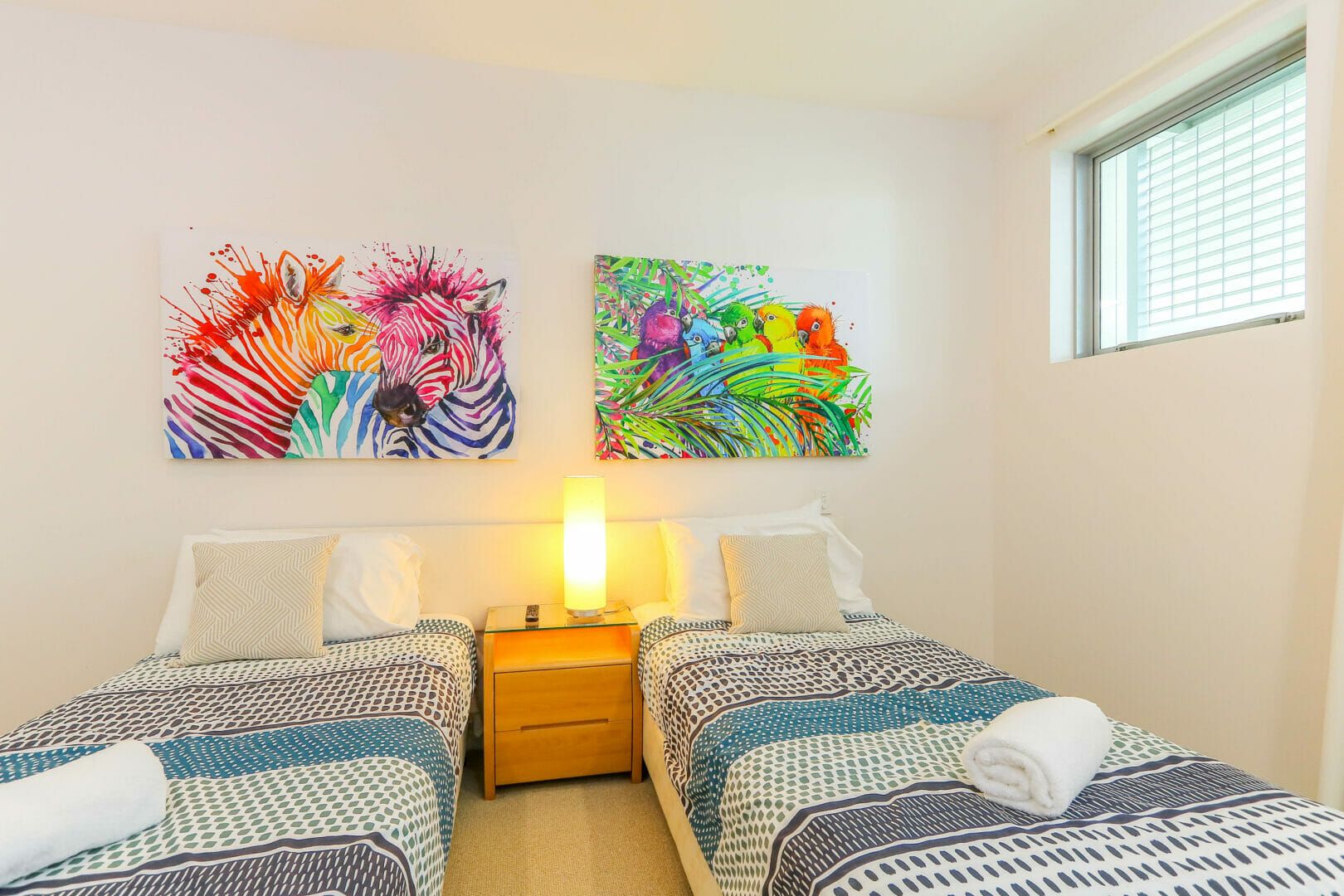 Twin beds with colourful art on walls