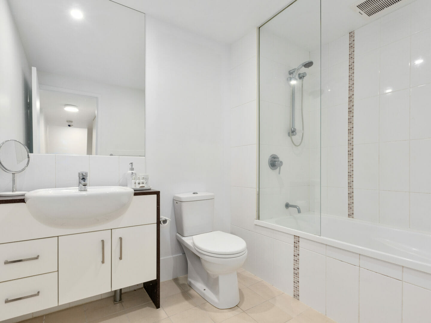 Bathroom with shower over bath, toilet and vanity basin