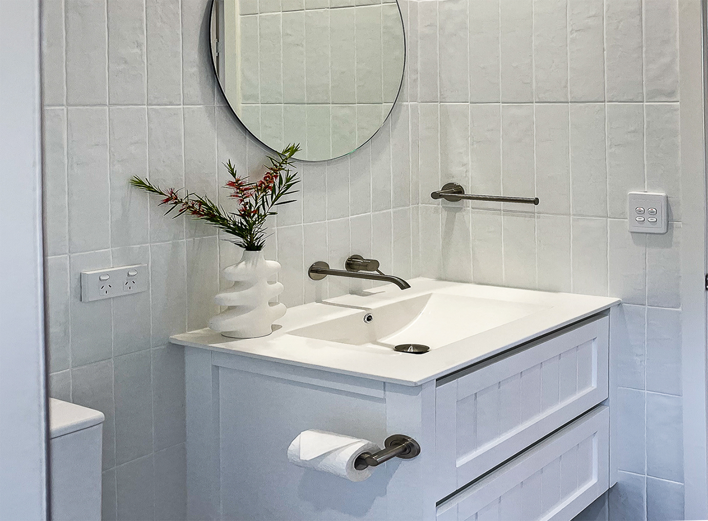 Bright white bathroom vanity with large round mirror